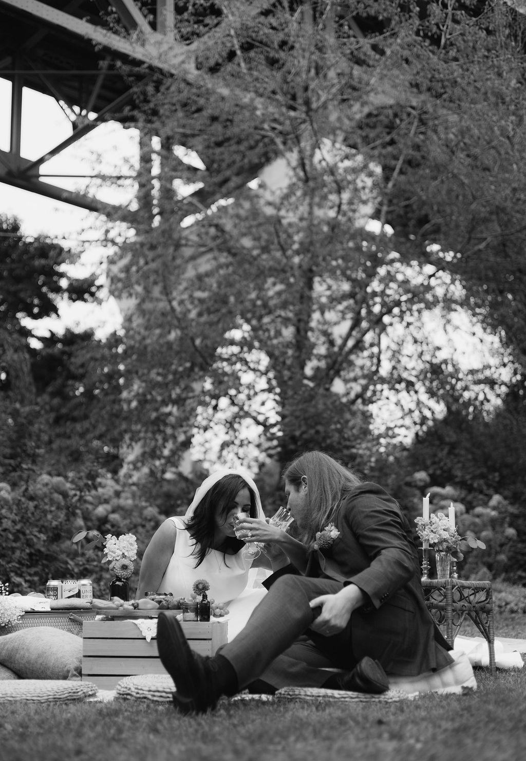 Black and white photograph of a couple drinking a toast under the St. Johns Bridge girders