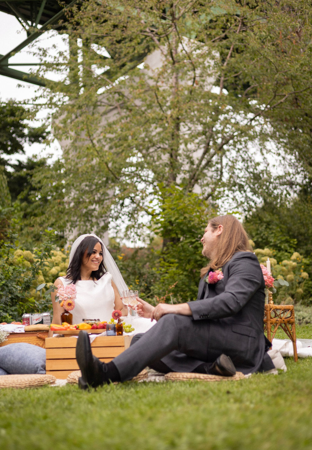 A couple toasting on picnic blankets beneath the St. Johns Bridge at Cathedral Park