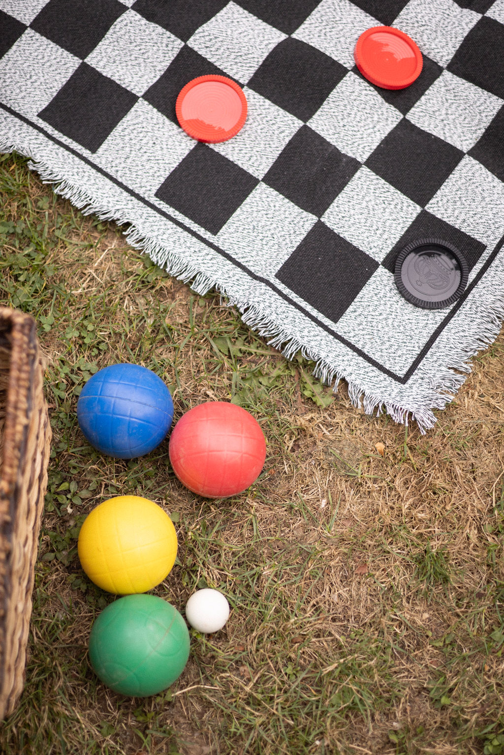 Bocce balls and a checkers blanket set out on the grass at a Cathedral Park picnic reception