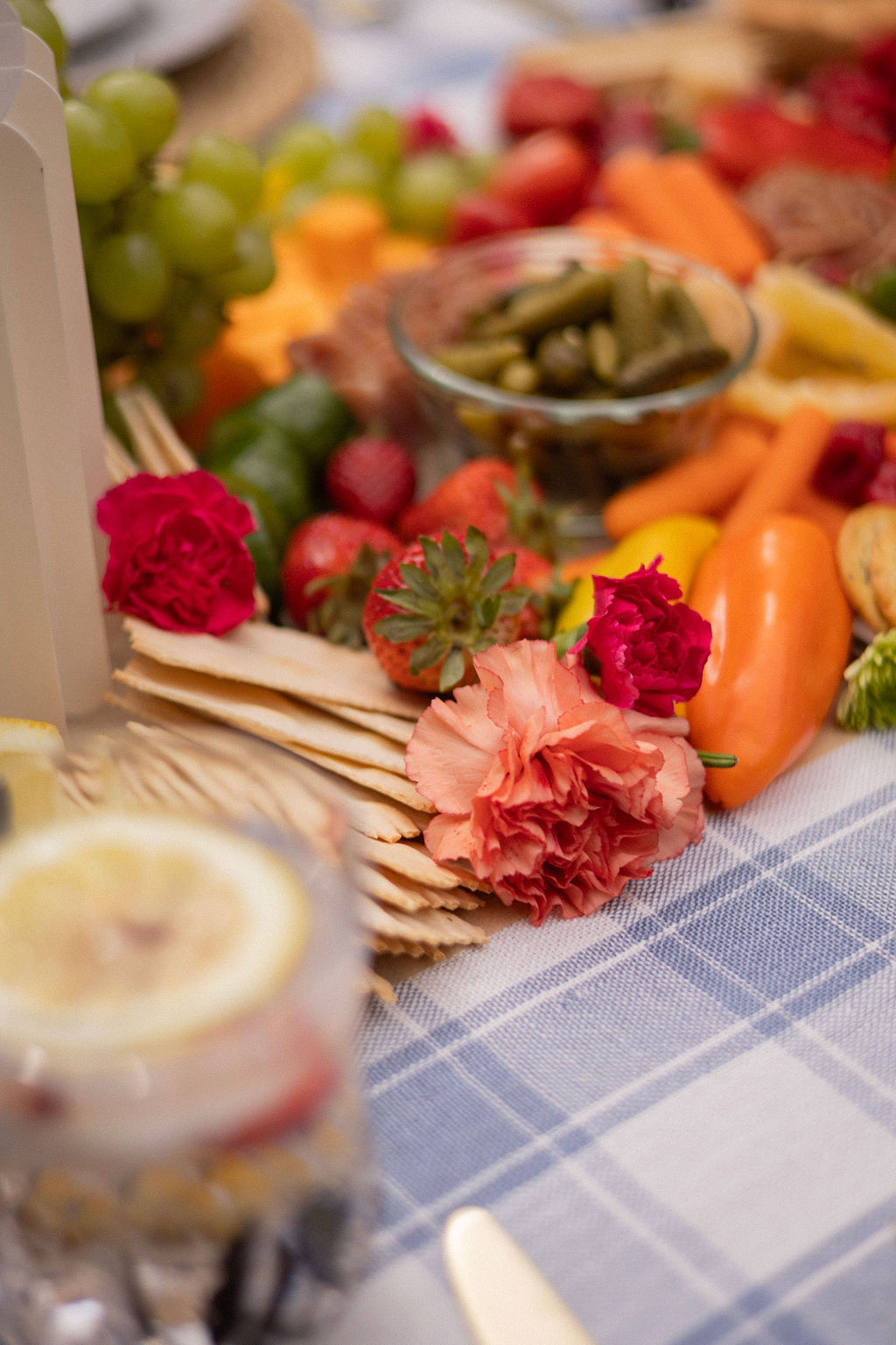 Carnations tucked among crackers, strawberries and peppers on the picnic table