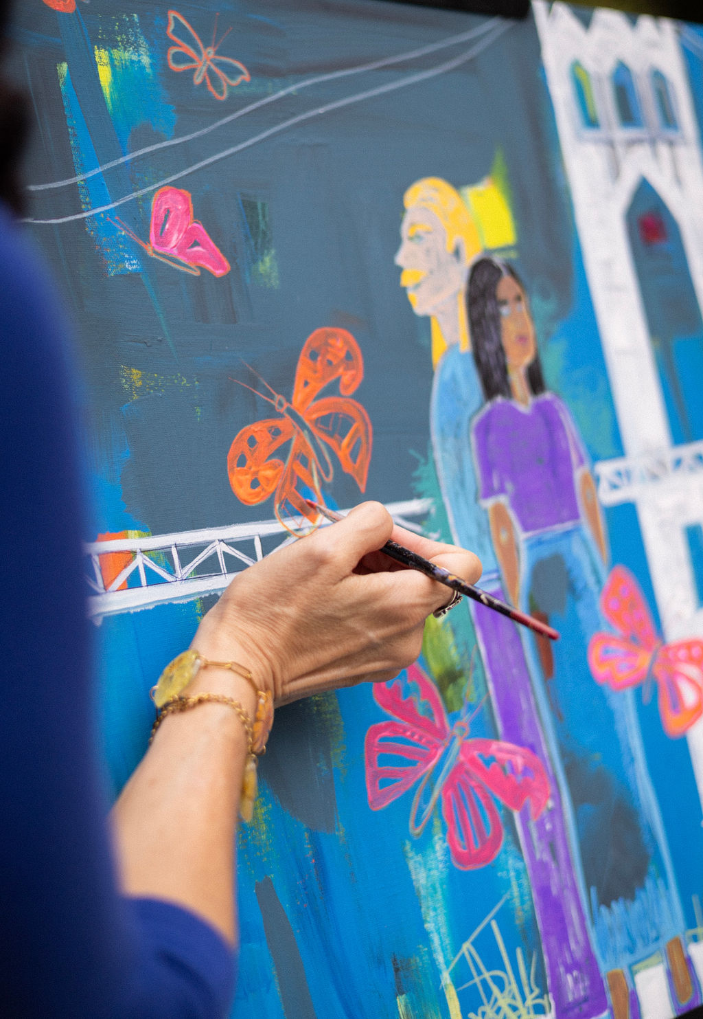 Close up of an artist painting butterflies and the St. Johns Bridge onto a live event painting canvas